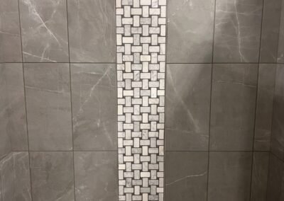 Gray tile shower with basketweave accent strip at Kentucky Tile Distributors in Owensboro, KY